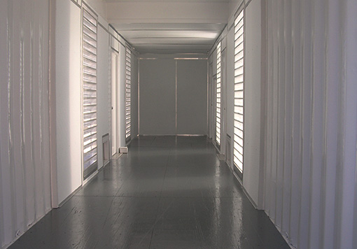 a white storage container with some ventilation on it, it also has a gray door and a gray floor.